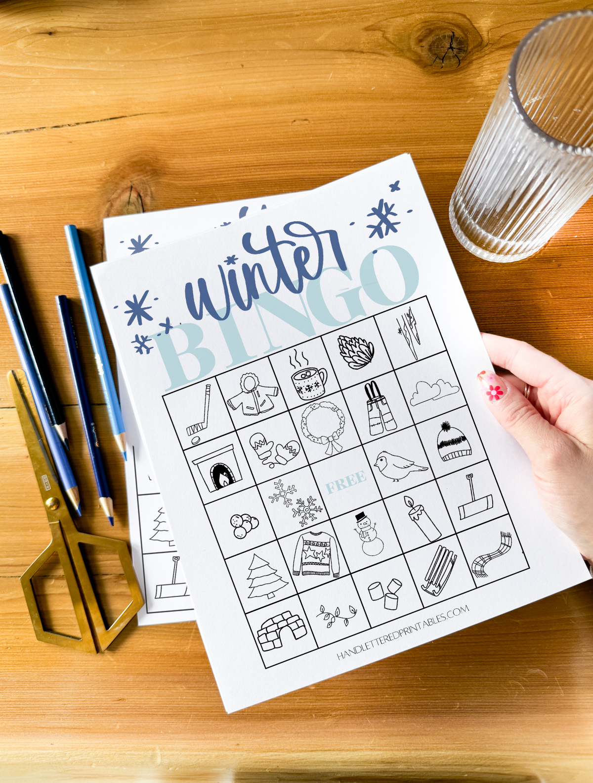 winter bingo card printed and being held above wood table