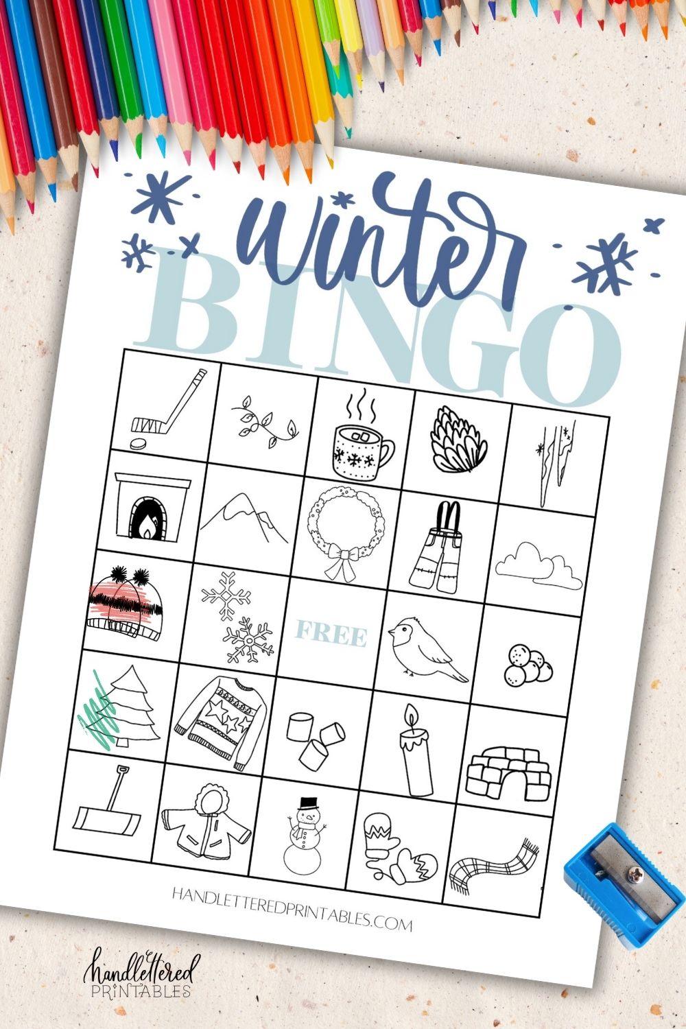 Free printable winter bingo card printed and being coloured with pencil crayons on countertop