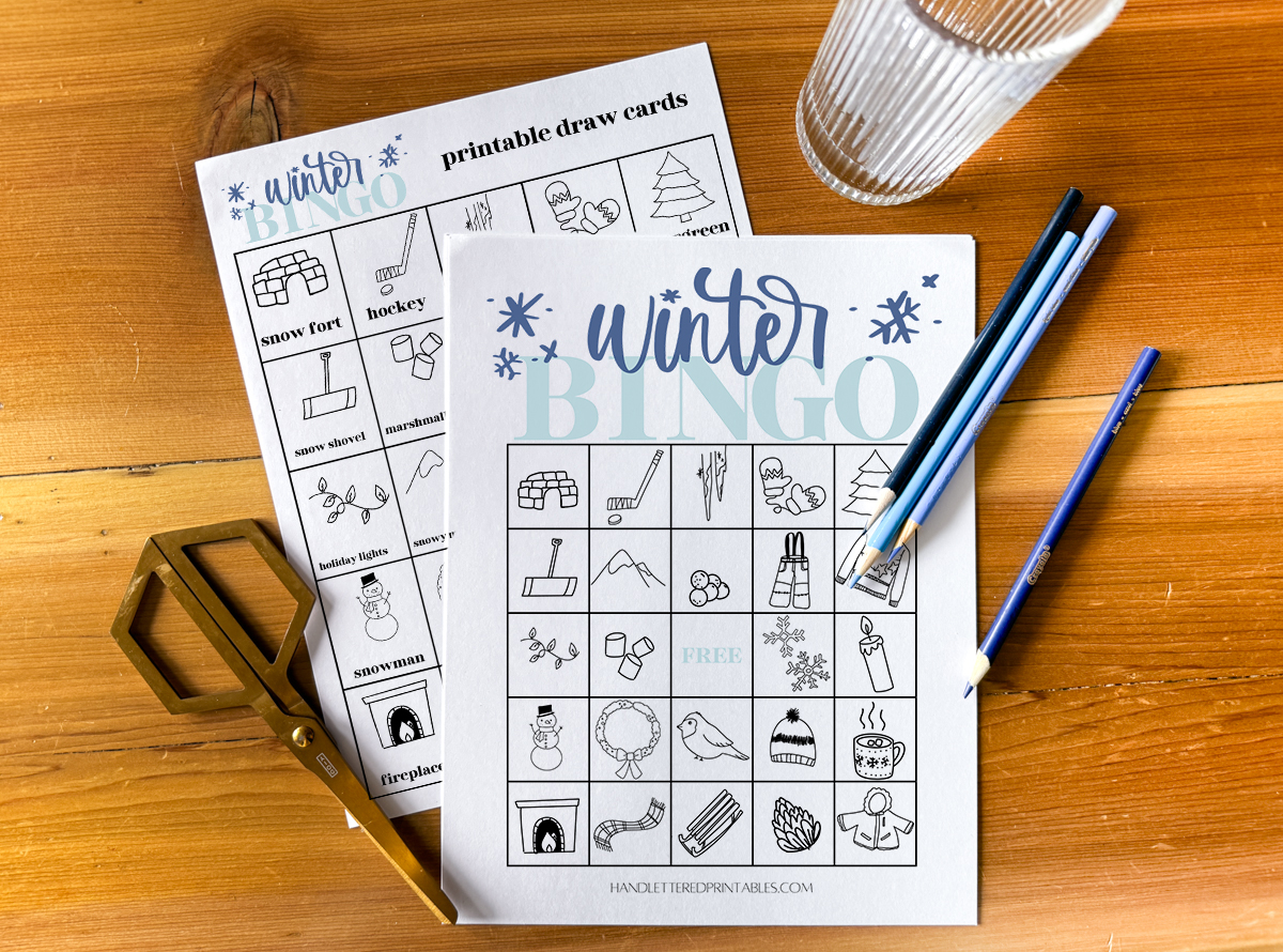 winter bingo card and calling cards printed on wooden table with gold scissors and blue pencil crayons