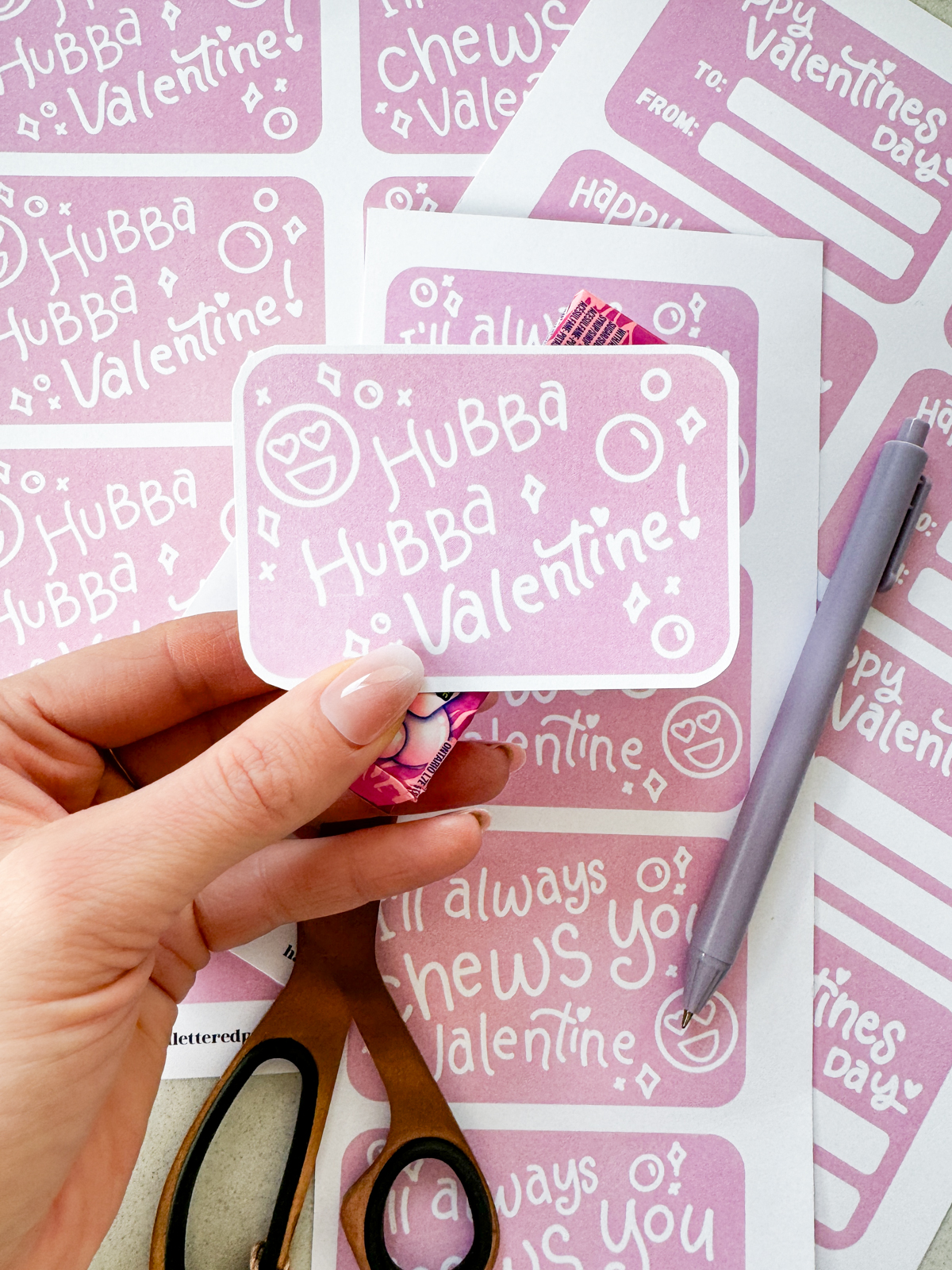 hubba hubba valentine cut with rounded corners and held with a pack of bubble gum free printables being cut to size on the countertop