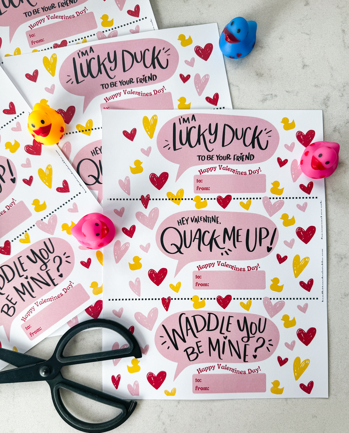 duck themed printable valentines day cards. card shown reads: waddle you be mine, hey valentine you quack me up and lucky to be your friend- all with a small happy valentines day. shown with rubber duckies, shown ready to be cut to size