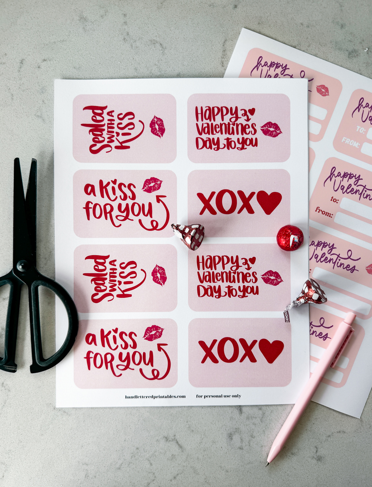 free printable valentines cards shown printed as full sheets, ready to be cut out. Front has 4 versions with pink backgrounds and red lettering that read 'sealed with a kiss' 'happy valentines day to you' 'a kiss for you' and 'xoxo' perfect for pairing with chocolate kisses