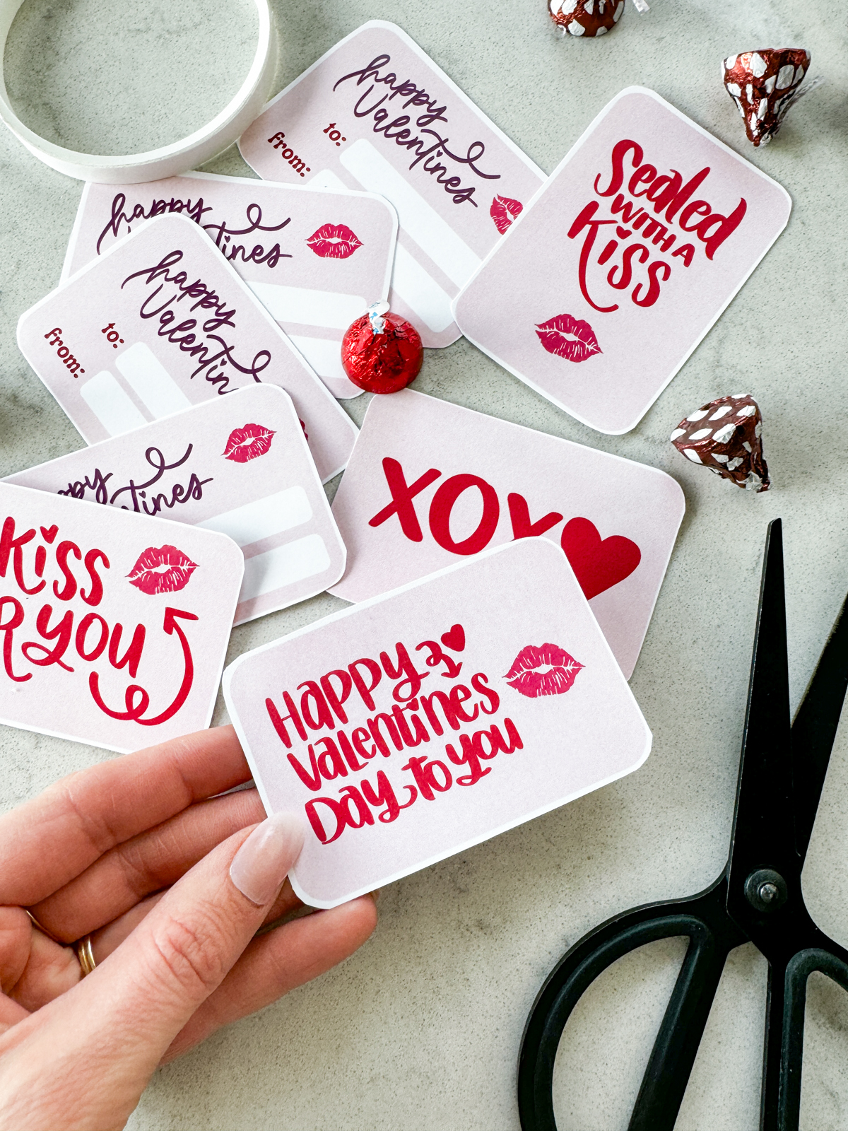 image of printable valentine cards being cut to size, valentines cards read: a kiss for you, xoxo, happy valentines day to you, sealed with a kiss