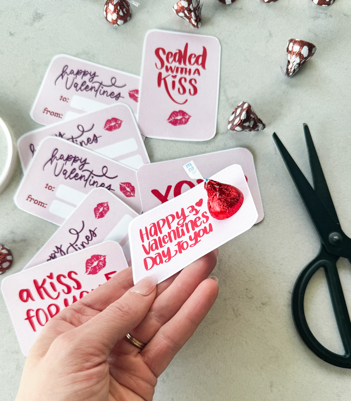 free printable valentines cards to pair with hershey's kisses. card being held says happy valentines day to you with red hersheys kiss attached to top with double sided tape