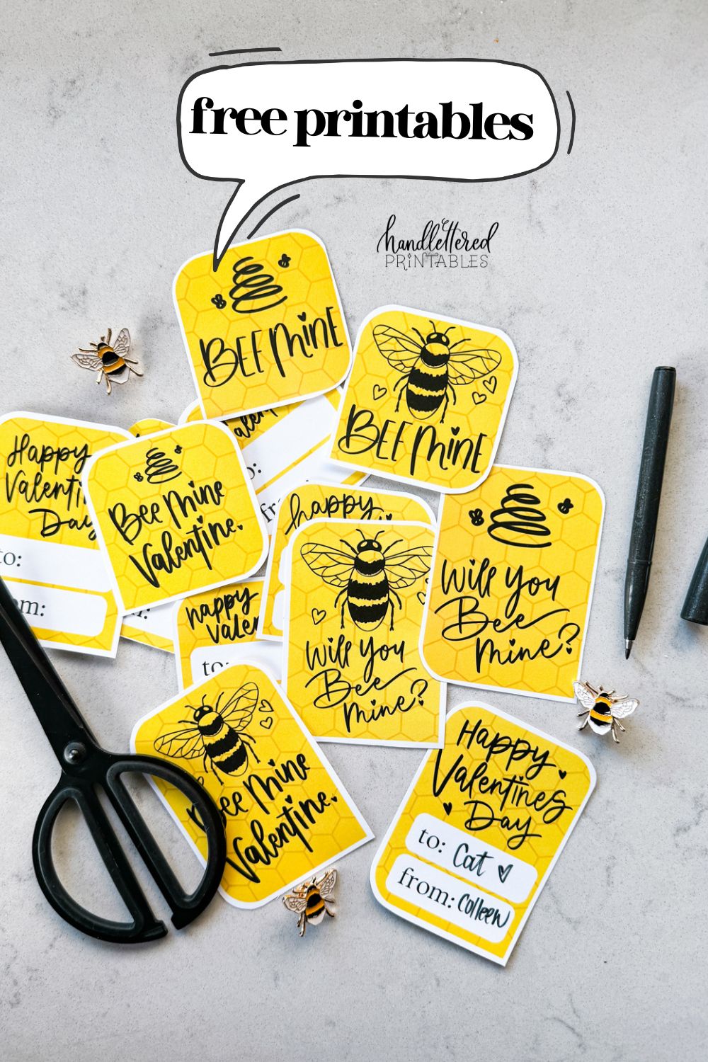 text over image reads 'free printables' image of bee themed valentines cards on countertop valentines cards read: bee mine, will you bee mine, and bee mine valentine with illustrations of a bee and of a line art bee hive. reverse has space for names and says 'happy valentines day'. all hand lettered in black ink with yellow honeycomb background