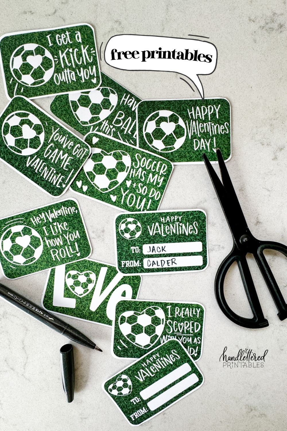 text reads: free printables image shows soccer themed valentines cut to size with rounded corners on a marble countertop and styled with a black pen and black scissors valentines have a heart shaped soccer ball and a soccer ball with a heart on it and a grass background. valentines puns and sentiments include: happy valentines day, have a ball this valentines, hey valentine i like how you roll, soccer has my heart and so do you, i get a kick outta you, love (with a heart soccerball as the o), you've got game valentine, and i really scored with you as a friend reverse reads 'happy valentines' with room for to and from names. soccer/ american football