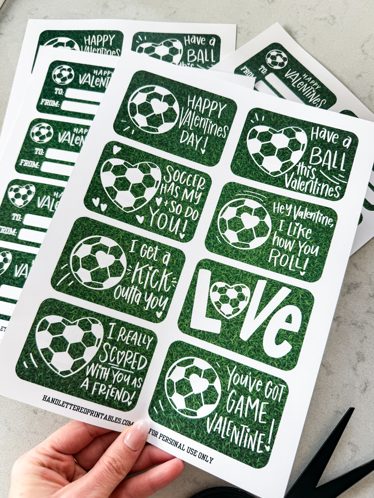 image shows soccer themed valentines cards printed in full sheets, ready to be cut to size valentines have a heart shaped soccer ball and a soccer ball with a heart on it and a grass background. valentines puns and sentiments include: happy valentines day, have a ball this valentines, hey valentine i like how you roll, soccer has my heart and so do you, i get a kick outta you, love (with a heart soccerball as the o), you've got game valentine, and i really scored with you as a friend reverse reads 'happy valentines' with room for to and from names. soccer/ american football