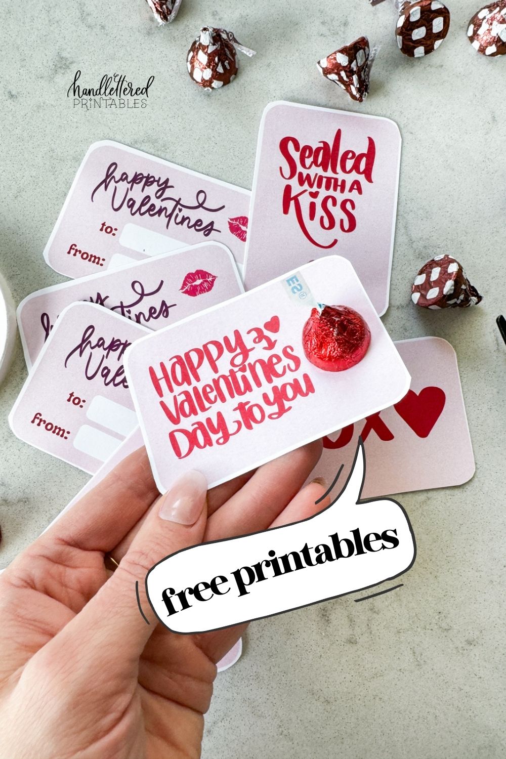 text reads: free printables card being held says happy valentines day to you with red hersheys kiss attached to top with double sided tape image of