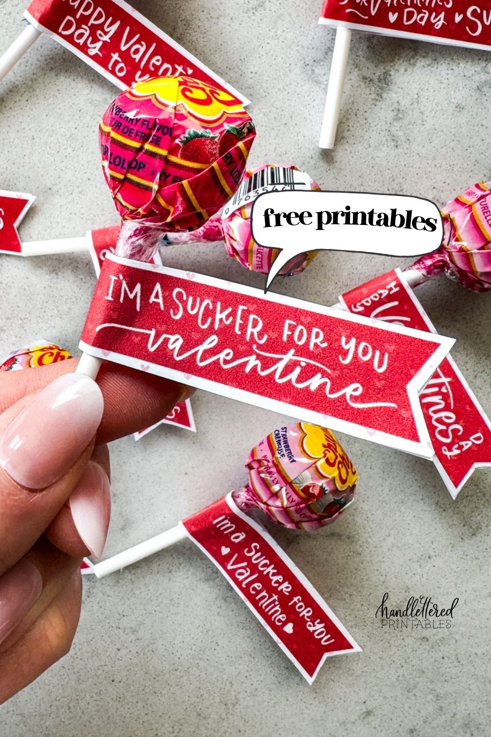 text reads free printable over image of holding a sucker with a free printable valentines tag on the stick like a flag that reads 'i'm a sucker for you, valentine'