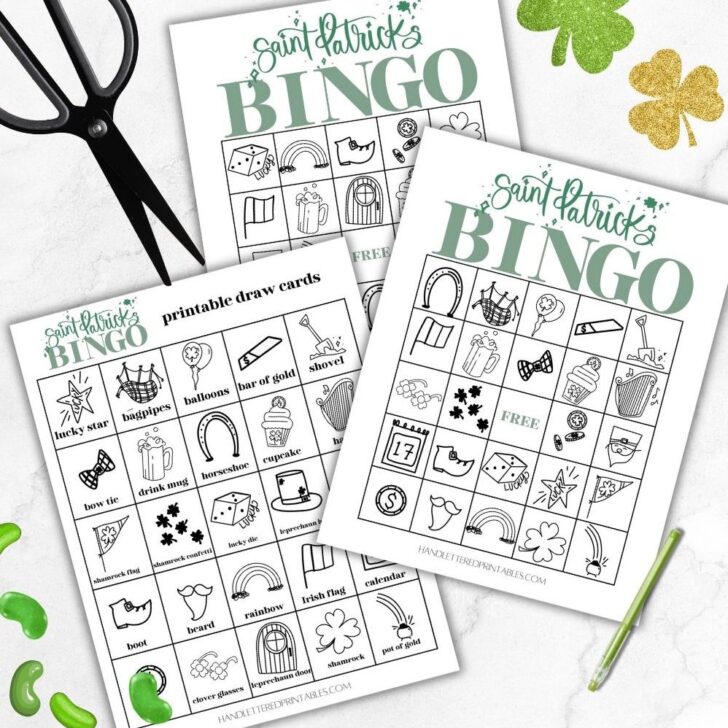 image of two printed saint patrick's day bingo cards with 1 printed saint patricks day bingo calling cards ready to be cut out on marble counter styled with black scissors and glittery shamrocks