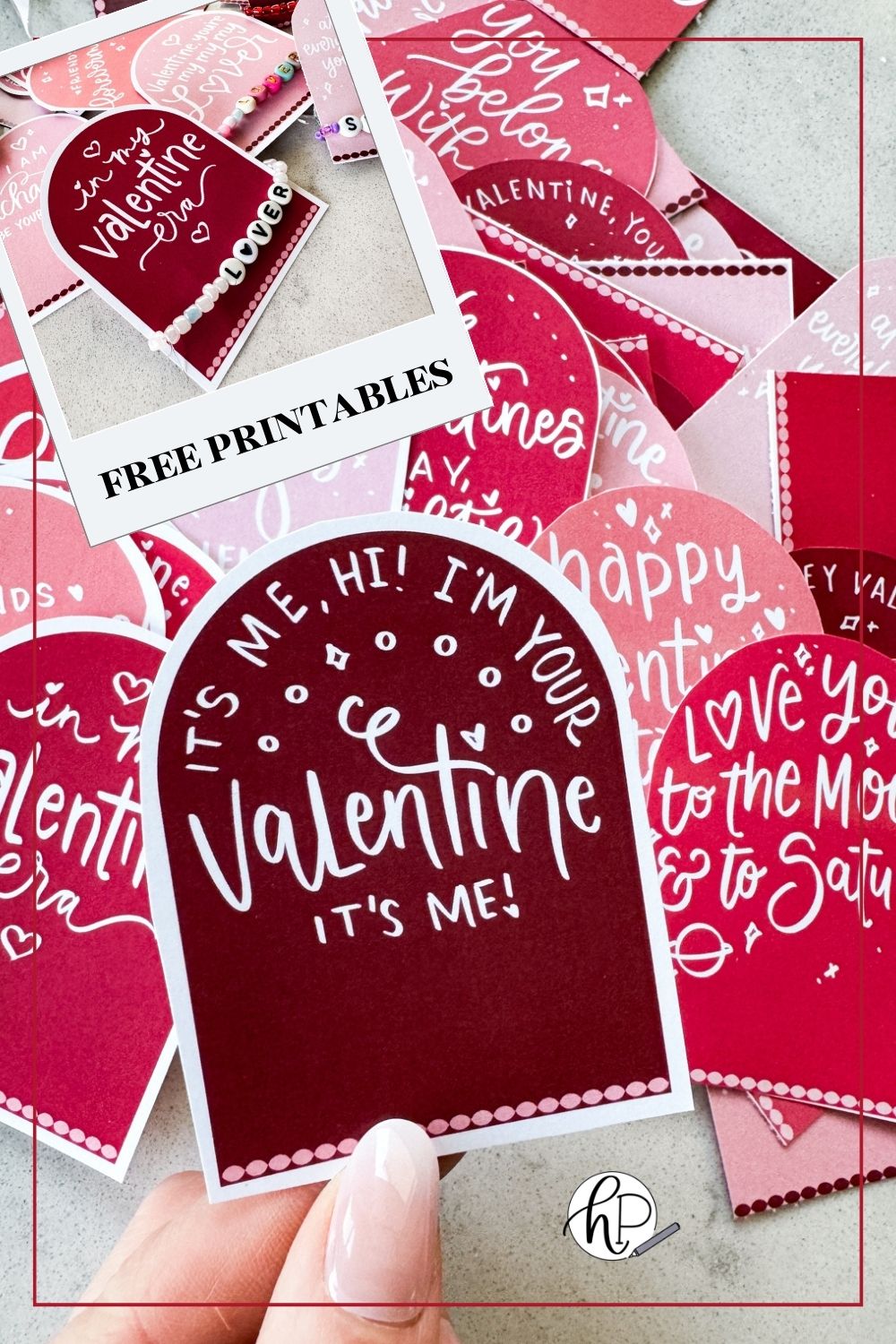 taylor swift themed valentines day cards printed and cut to size (arch shaped pink and deep burgundy color with white hand lettered song lyrics) shown on marble countertop. held valentine reads: it's me, hi! i'm your valentine, it's me! image overlay shows a valentine that reads 'in my valentine era' with a 'lover' friendship bracelet as the favor. text over reads: free printables