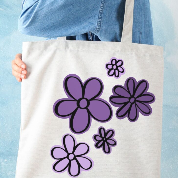 Free SVG- Hand Drawn flowers cut files shown cut with layers on a tote bag, the background layer is cut in a variety of purples and black outline