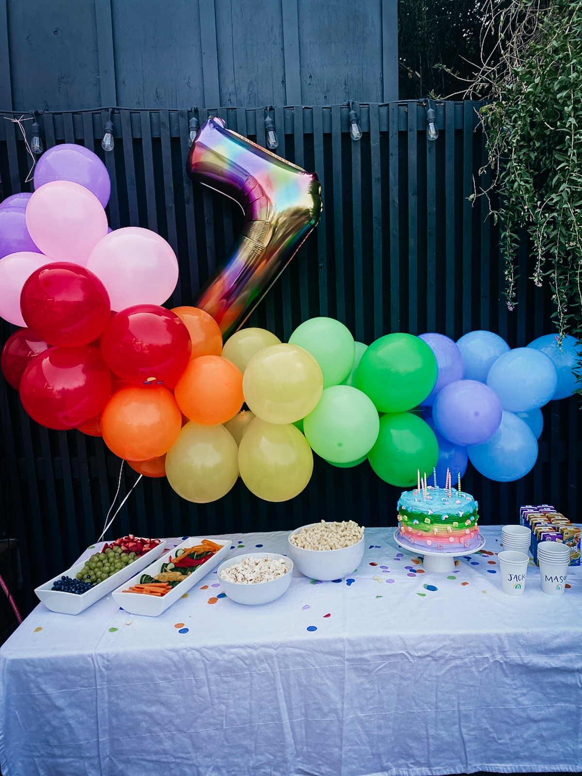 Rainbow birthday party table with rainbow balloon arch and lucky charm cake