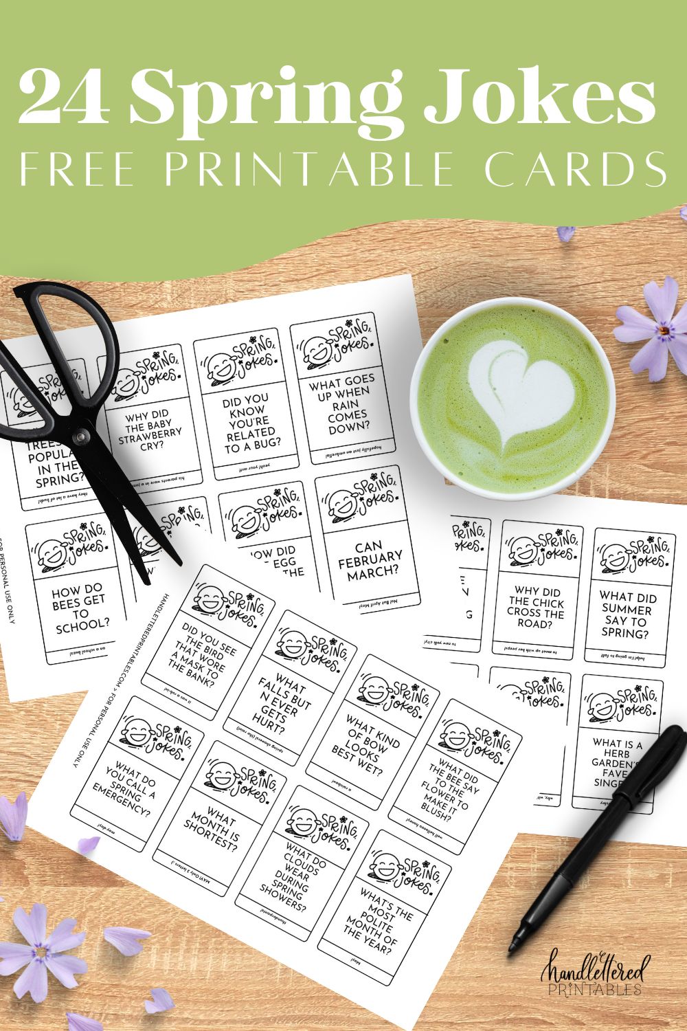 image of the black and white version of the spring jokes cards free printable printed on a wooden table with purple flowers, a matcha latte, pen and scissors. joke cards feature a hand lettered title and illustrated laughing emoji with the jokes.