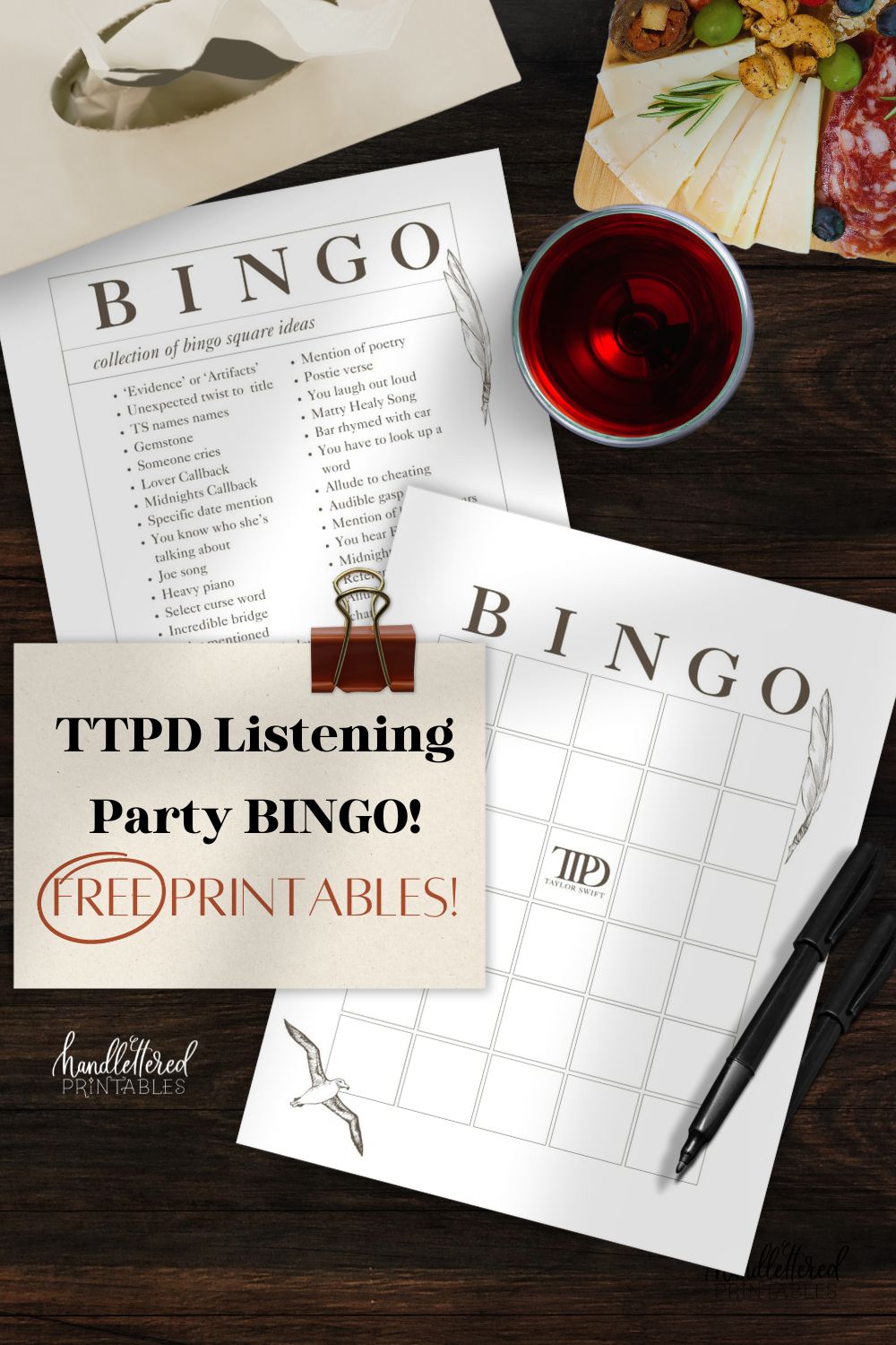 image of printed bingo card and suggestion list with a TTPD theme (taylor swift tortured poets department) on a dark wood table with a box of tissues, charcuterie board, glass of wine and pen. Title text is styled on a note card and reads: TTPD Listening Party bingo! FREE printables.